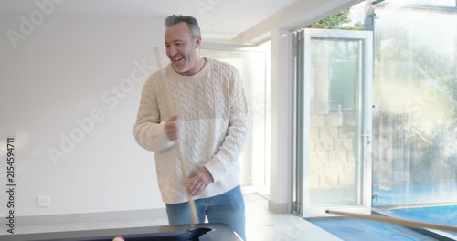 Diverse male friends playing pool in game room, cream-sweater entering, gray taking shot for fun