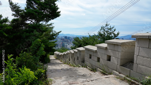 Historic Seoul City Wall (Hanyangdoseong) hiking trail with stone steps overlooking modern cityscape, South Korea
