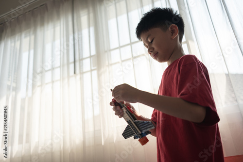 Close-up of a child building a toy airplane with plastic blocks indoors. Suitable for education, creativity, and childhood development themes.