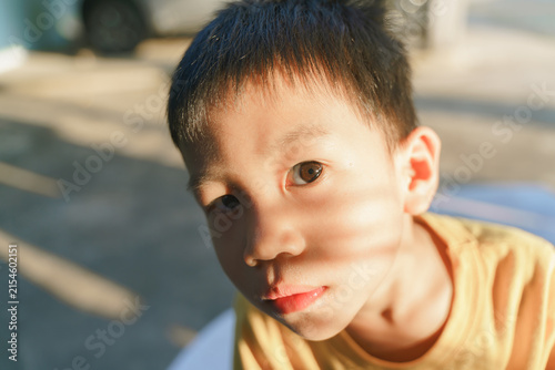 Close-up portrait of a young boy under warm sunlight, highlighting his expressive gaze and gentle features.