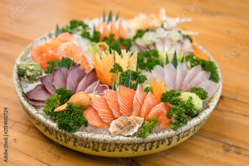 A beautifully arranged Japanese sashimi platter with fresh salmon, and shellfish on ice, garnished with vegetables., tuna, white fish