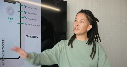 TV showing app mockup non-binary African lead wearing mint top explaining app, pointing in meeting