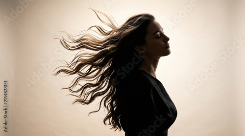 Woman silhouette with windblown long wavy hair