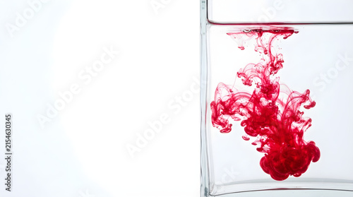 red ink swirling in clear water inside glass container with copy space