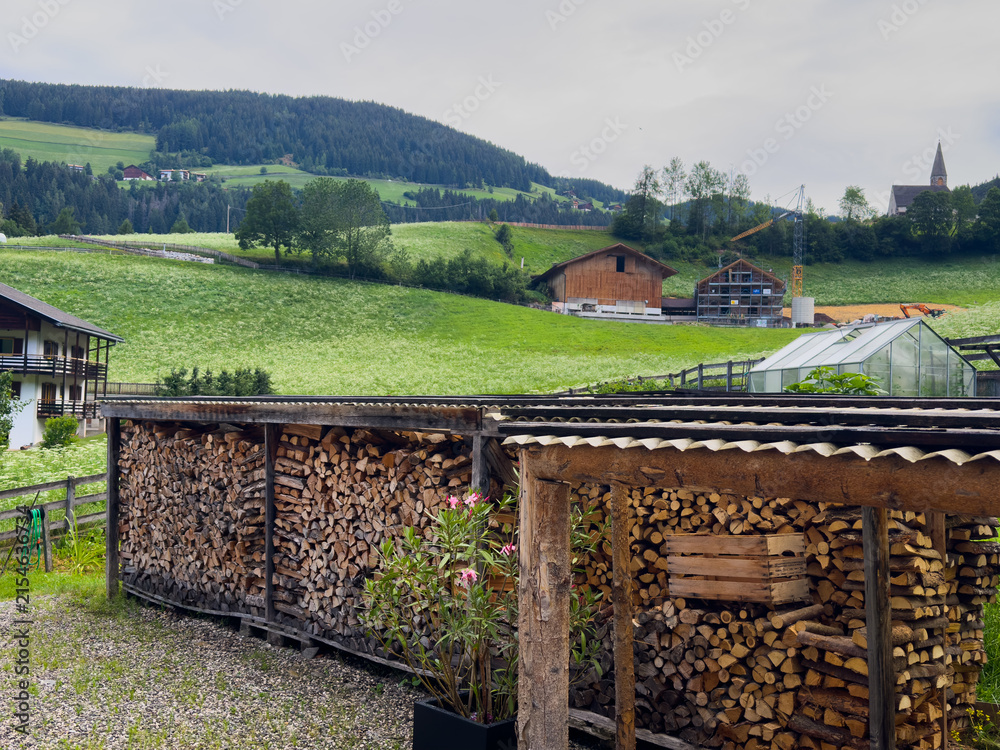 Obraz premium traditional alpine village, featuring rustic wooden buildings and lush green mountain slopes under a bright blue sky