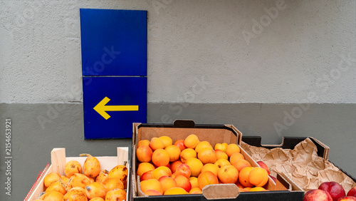 Yellow Arrow Camino Sign Above Cardboard Crates of Apricots