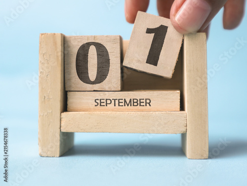 Cuadro en lienzo A woman's hand is holding a wooden block with the number 1 written on it on a wooden block calendar for September 1st on a light blue background
