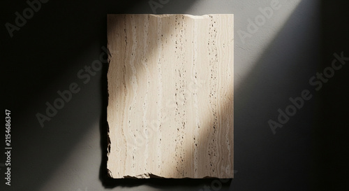 Minimalist travertine stone slab on dark wall with dramatic light