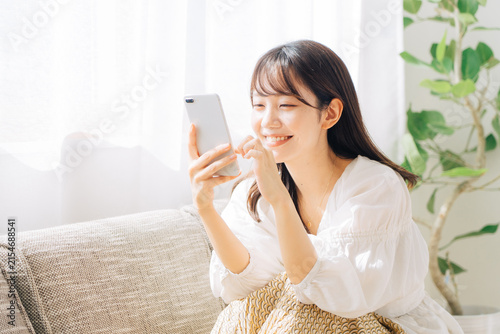 ソファに座ってスマホを見る女性