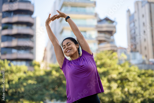 Foto Woman, stretching and smiling in city with fitness, arms overhead or wellness outdoor