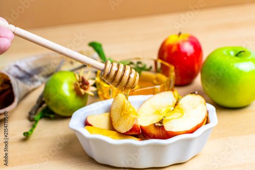 Hand dripping honey on apples for rosh hashanah