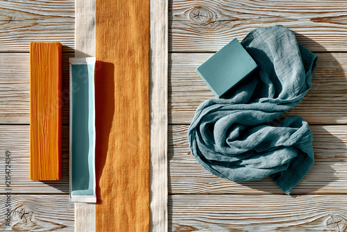Surfboard wax bars beside a folded striped towel on wood planks