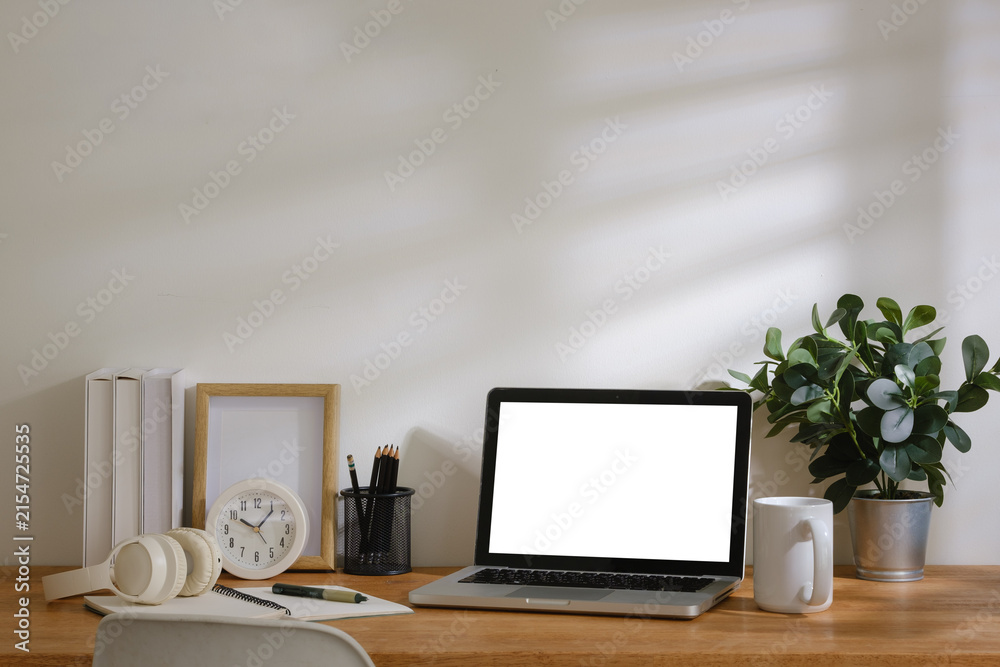 Fototapeta premium Modern home office workspace with laptop mockup screen, calculator, notebook, headphones, coffee cup and stationery on wooden desk.