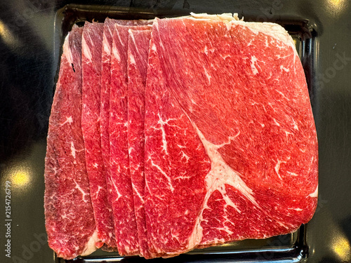 Rare beef with marble texture on black tray. Red beef Sliced Asian shabu shabu Sukiyaki food style. Japanese style food. Beef shabu set.