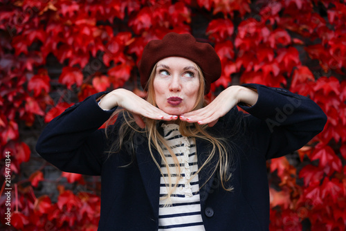 Female portrait with bright red foliage, cheerful mood and fall season vibes.