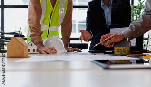 Construction team and real estate professionals analyzing blueprints and architectural drawings, planning future home building