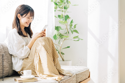 ソファに座ってスマホを見る女性
