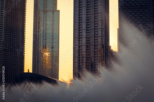 Sunset urban cityscape with water fountains and glass skyscrapers in Dubai, UAE