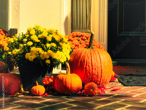 Pumpkins and flowers in front of a porch during the Halloween season