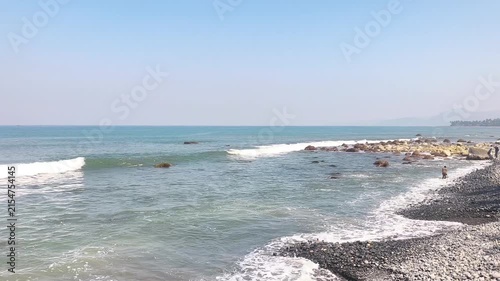 Waves crashing on a rocky pebble beach on a sunny day