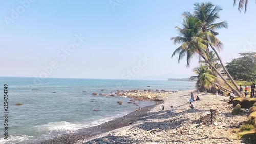 Aerial view of rocky coastal spit with palm trees and people