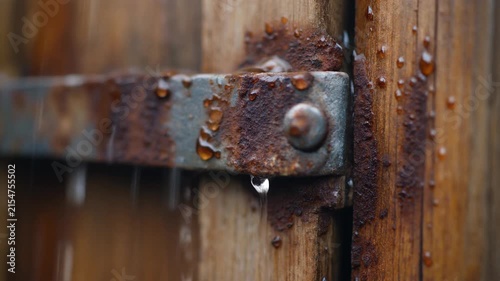 A close-up view shows a rusted metal hinge attached to weathered wooden planks.