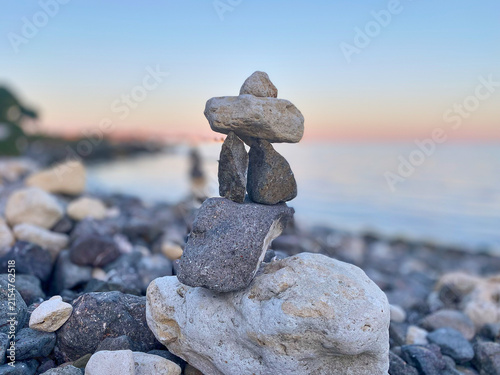 Photography Stone sculpture formed by balancing rocks on a pebbled beach with a calm water s