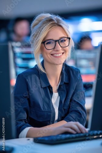 Blonde woman smiles confidently at computer screen