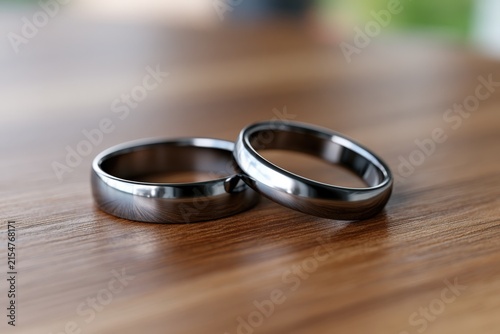 Two sleek, modern rings rest on a warm wooden surface
