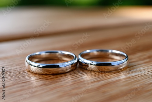 Two elegant silver rings rest side by side on warm wood