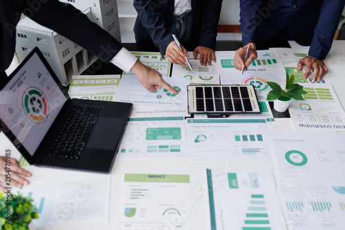 Business people analyzing esg reports on sustainability, green economy, and environmental impact strategies, using data on laptops and papers