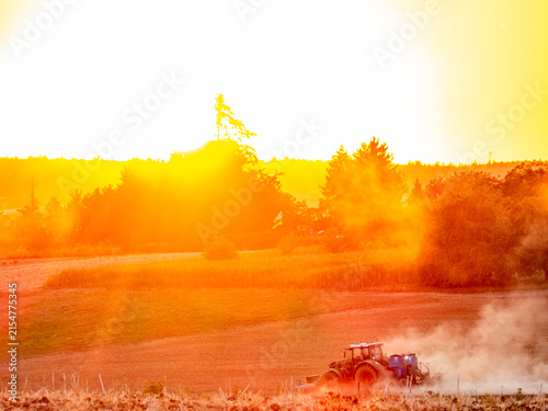 Foto Traktor wirbelt Staub auf bei Sonnenuntergang