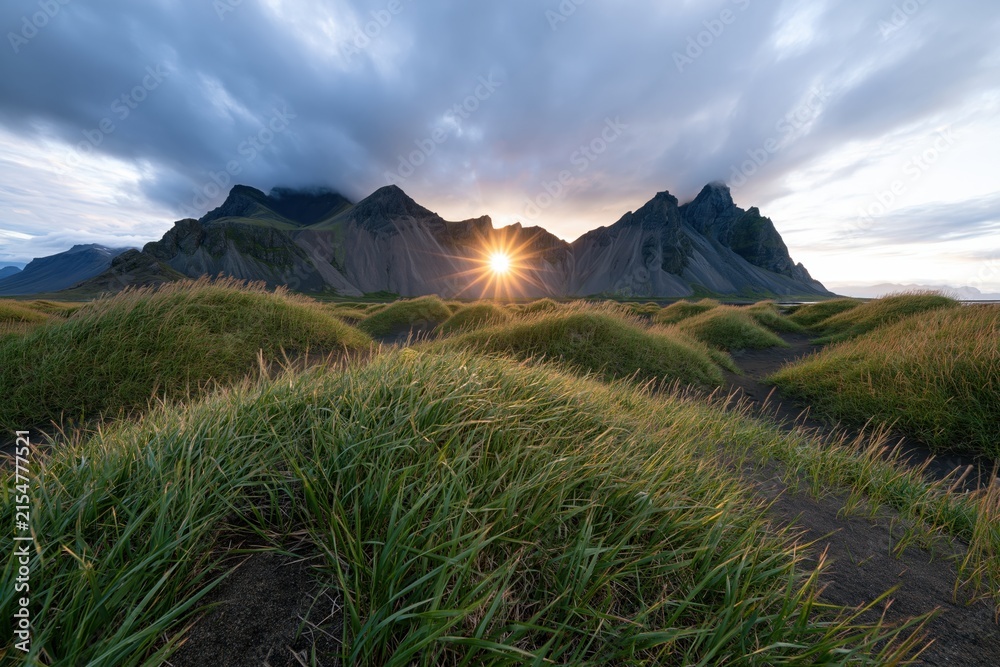 Obraz premium The Sunrise Over Rugged Mountain Range Amid Rolling Grasslands At Dawn