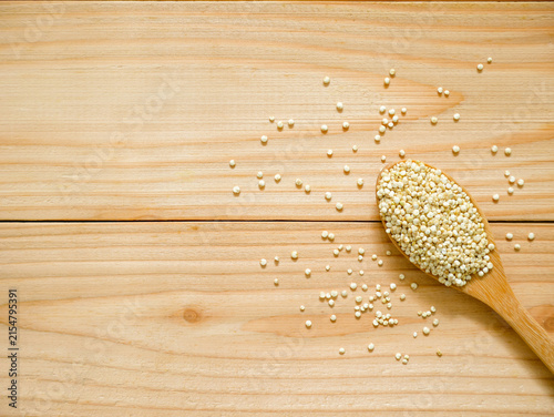 Pile of uncooked white quinoa in wooden spoon