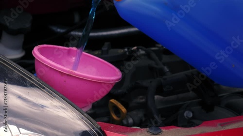 Driver putting windscreen wash fluid into car 