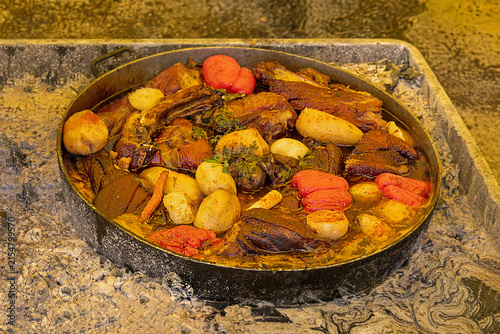 Fresh organic vegetables and pork meat with spices cooked in metal pot and sold outside on market