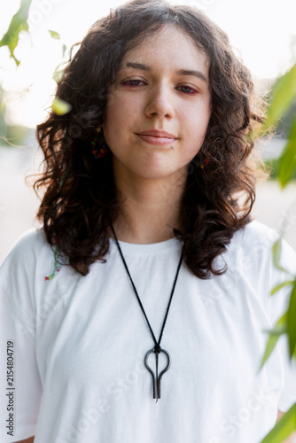 Fotografie Young woman with curly hair wearing jaw harp necklace outdoors