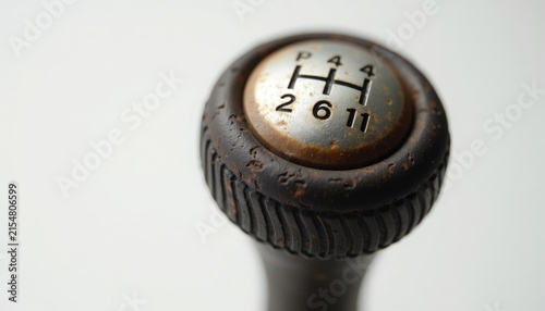 gear shift knob close-up showing worn leather collar, rusty trim ring and scratched metal cap with six speed shift pattern, manual transmission detail emphasizing tactile texture and patina,