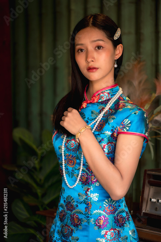 Photography Beautiful young Chinese woman wearing a vibrant silk qipao and vintage pearl nec