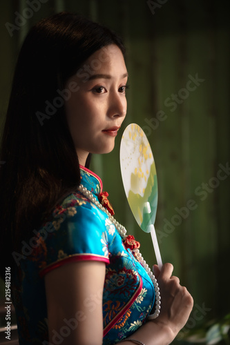 Photography Pretty young Chinese woman wearing a vibrant silk qipao and vintage pearl neckla