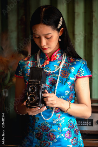 Photography Young Chinese woman wearing a vibrant silk qipao and vintage pearl necklace hold