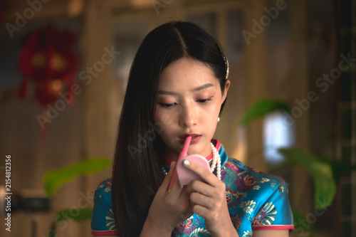Photography Pretty Chinese woman wearing a vibrant traditional silk blue qipao and pearl nec