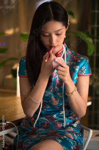 Photography Young Chinese woman wearing a vibrant traditional silk blue qipao and pearl neck