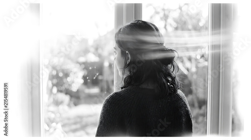Woman silhouette by window in soft morning light with gentle bokeh and reflective mood for lifestyle and wellness concepts