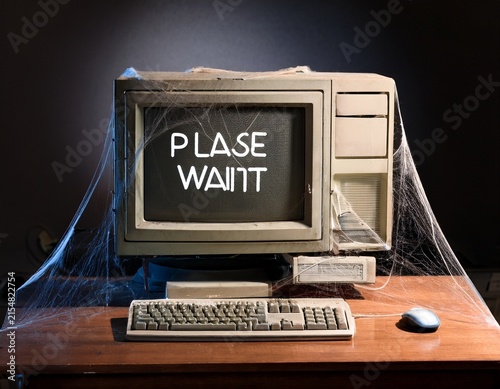 old computer on desk with cobwebs and please wait on screen