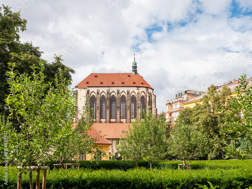 Photography Franciscan Garden with the Church of Our Lady of the Snows in central Prague, Czech Republic, featuring lush greenery and historic Gothic architecture near Wenceslas Square