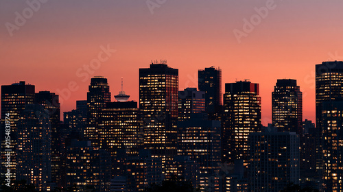 Abstract minimalist cityscape silhouette against a vibrant gradient sky, soft glowing window lights across building facades, no people, artistic urban concept, copy space on the ri