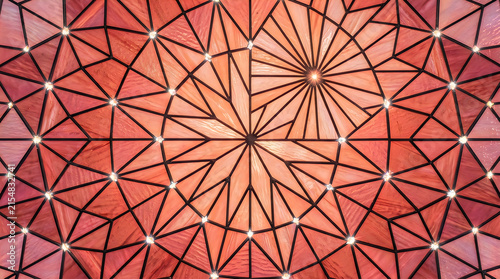 Geometric stained glass pattern with warm orange and pink hues during daylight