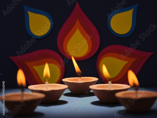 Clay diyas with flickering flames illuminate a festive backdrop