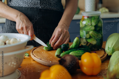 Person cutting fresh cucumbers for pickling in kitchen